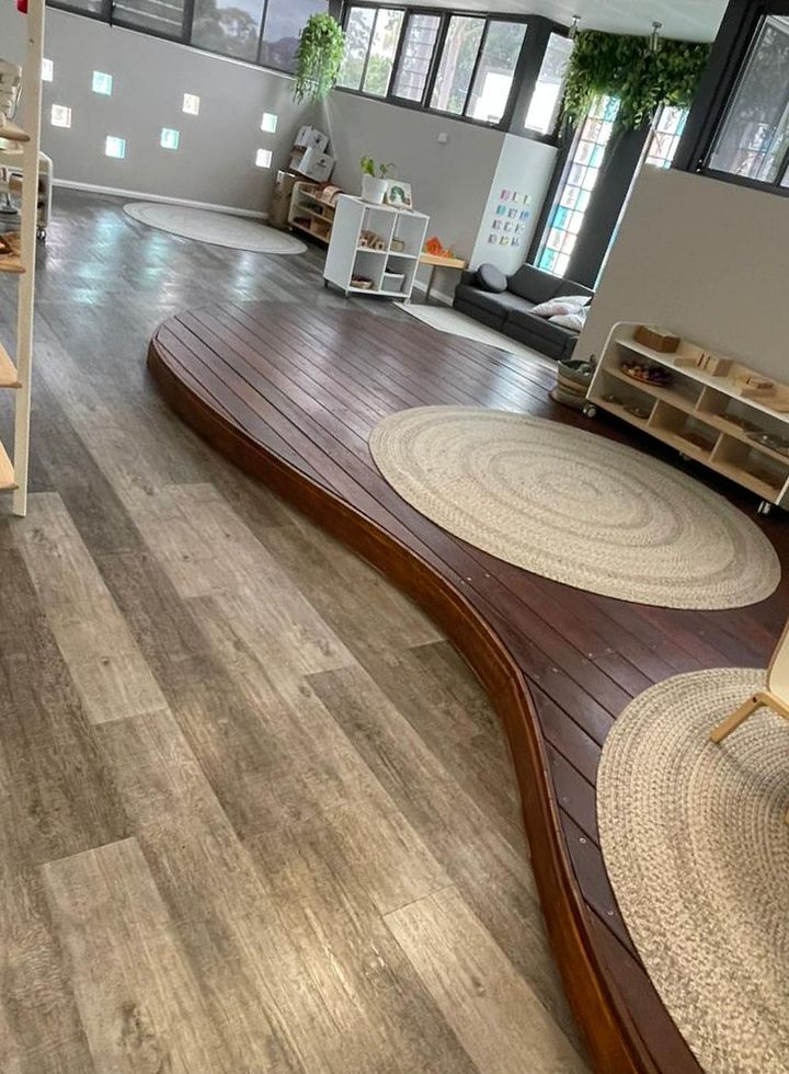 Early learning room with timber floors, woven rugs and low shelving