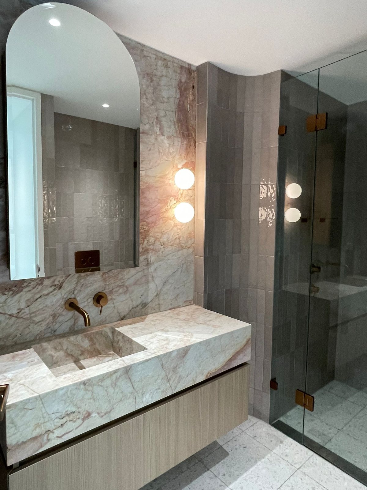 Stone vanity, brass tapware and shower screen after a final clean